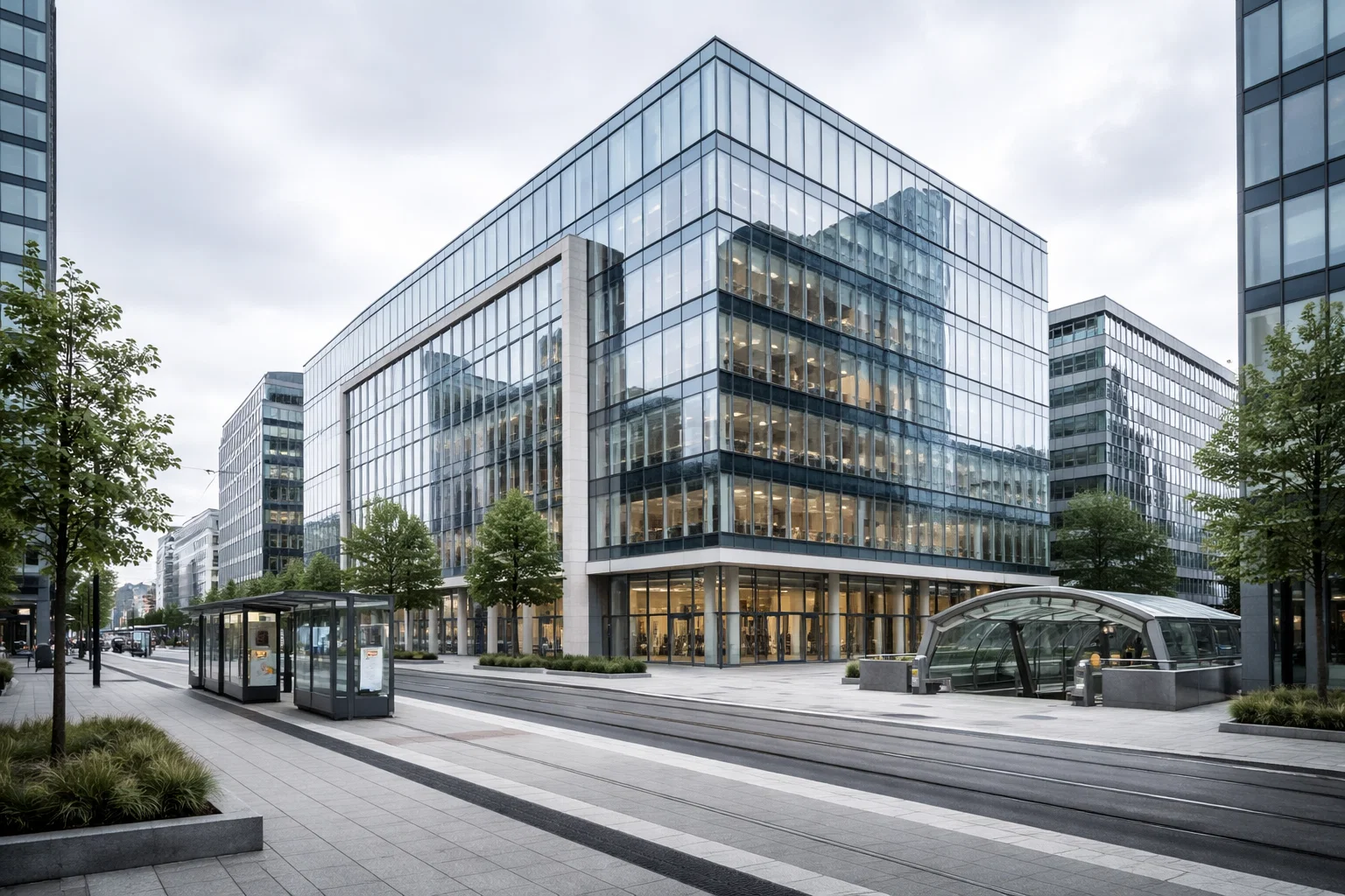 Immeuble de bureaux moderne en quartier d’affaires urbain, proche tram et métro.